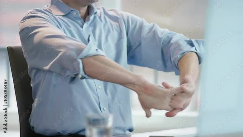 business man at office desk rolling up left sleeve, stretching fingers business man at office desk rolling up left sleeve, stretching fingers
