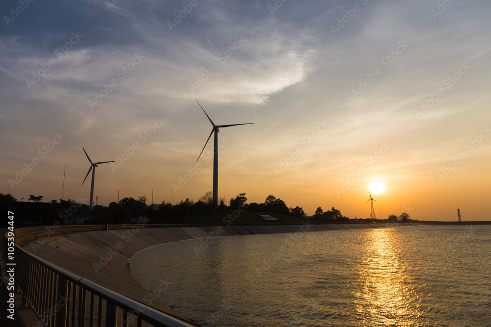 power generator wind turbines at sunset with reservoir