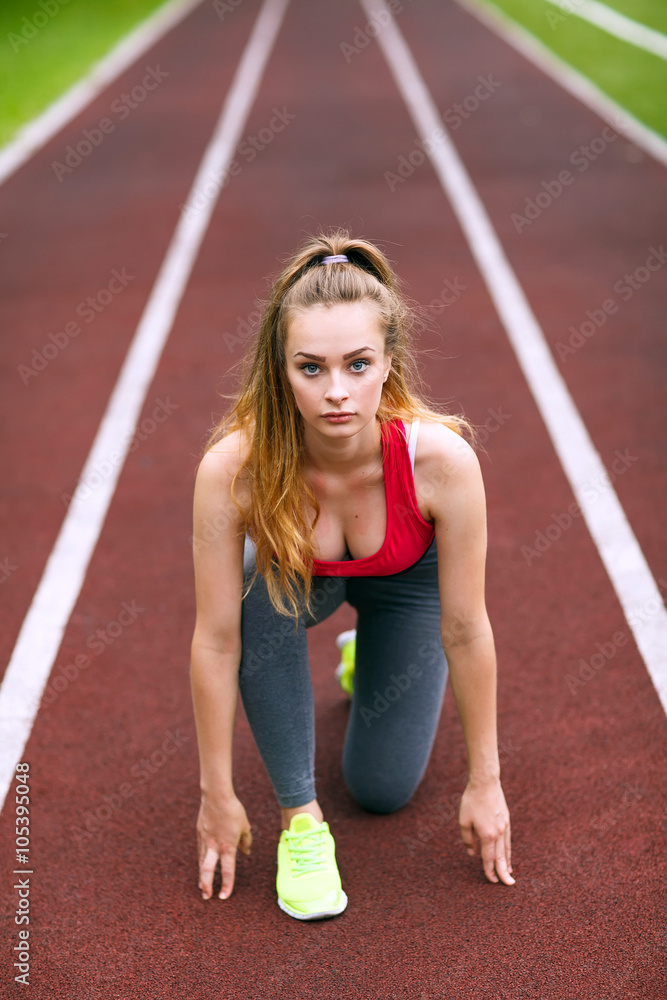 Beautiful athlete on a race track is ready to run