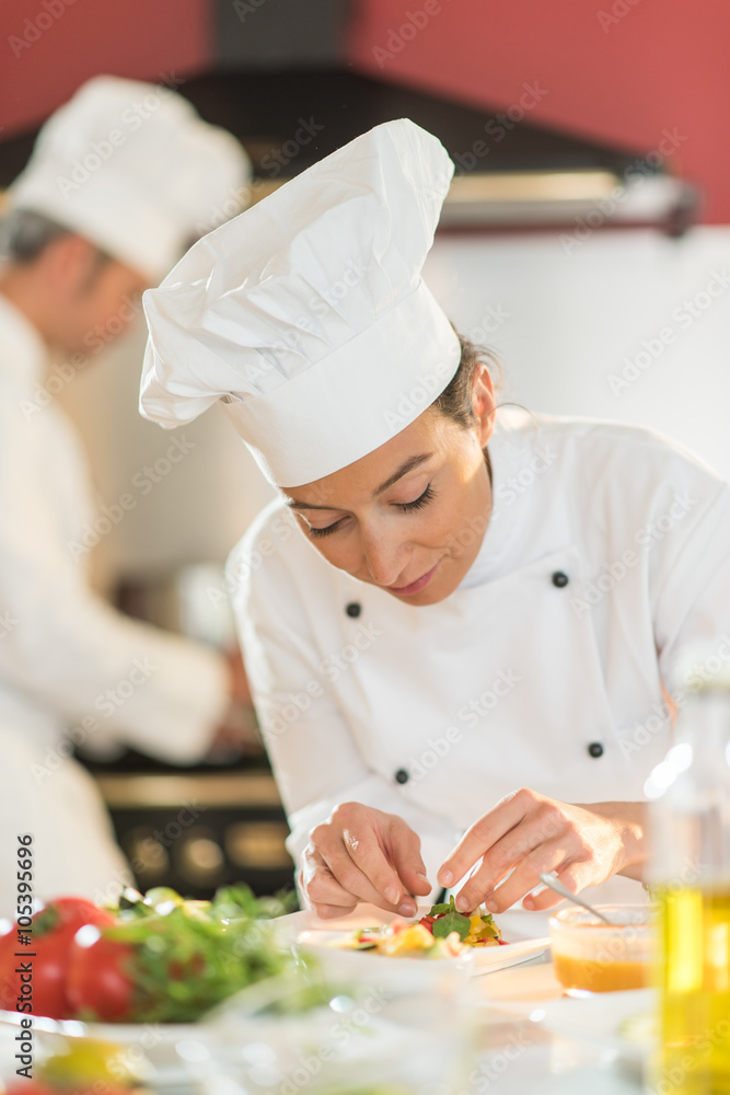 Portrait of a woman chef putting herbs on a plateful Portrait of a woman chef putting herbs on a plateful