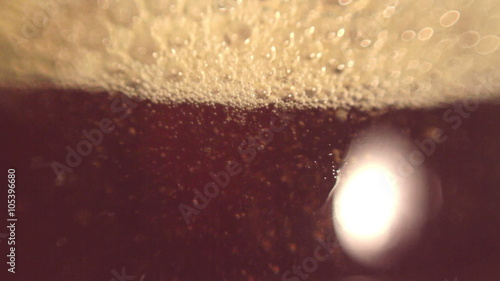 Elite dark beer is being poured into a curved glass photo
