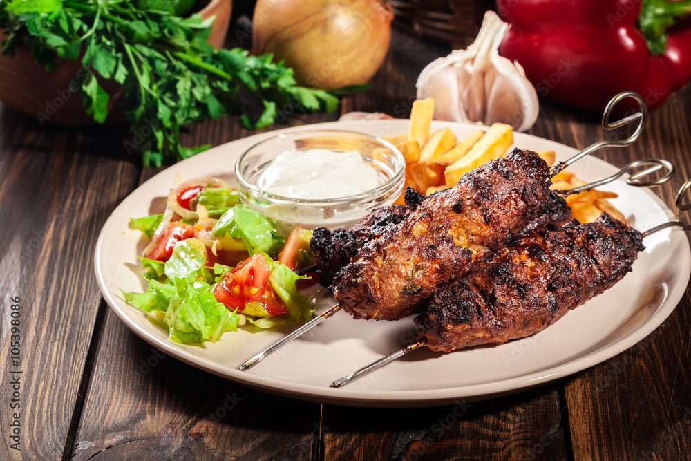 Grilled shish kebab served with fried chips and salad Grilled shish kebab served with fried chips and salad