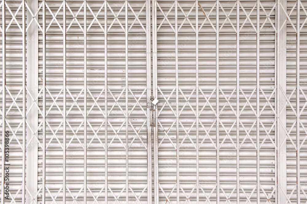 Obraz premium Closed shutters and metal accordion gate of a shoplot with focus on padlock