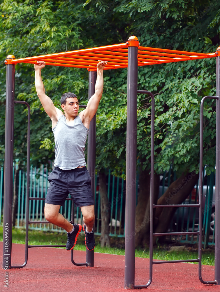 Fototapeta premium Muscular man doing pull-ups on horizontal bar