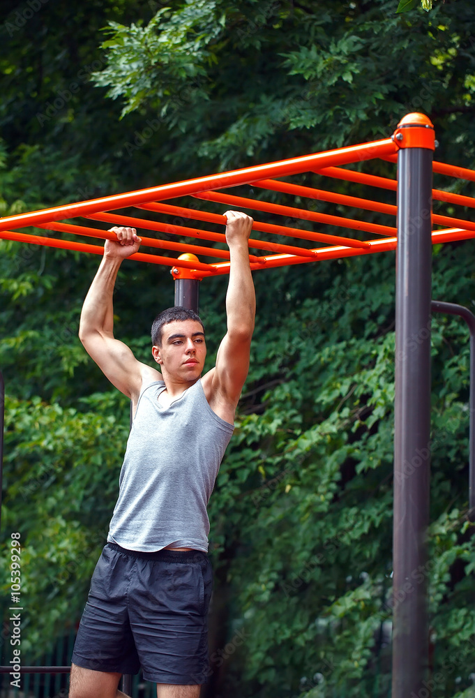 Muscular man doing pull-ups on horizontal bar Muscular man doing pull-ups on horizontal bar