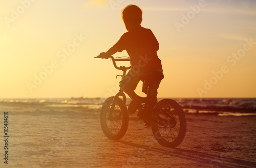 little boy riding bike at sunset
