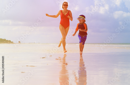 mother and son running in water on beach