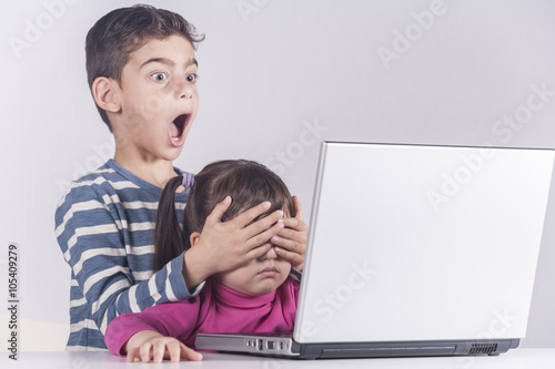 Little boy protects his sister from watching inappropriate content while using a computer. Internet safety for kids concept