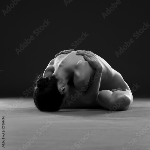 Naked yoga. Beautiful sexy body of young woman on gray background