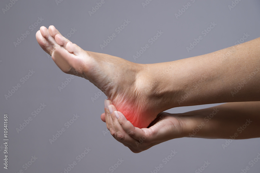 Pain in the foot. Massage of female feet. Pain in the human body on a gray background Pain in the foot. Massage of female feet. Pain in the human body on a gray background