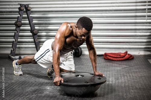 Muscular man doing push up on bosu ball photo