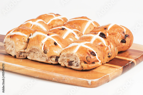 Hot cross buns on a timber board with a white background. photo