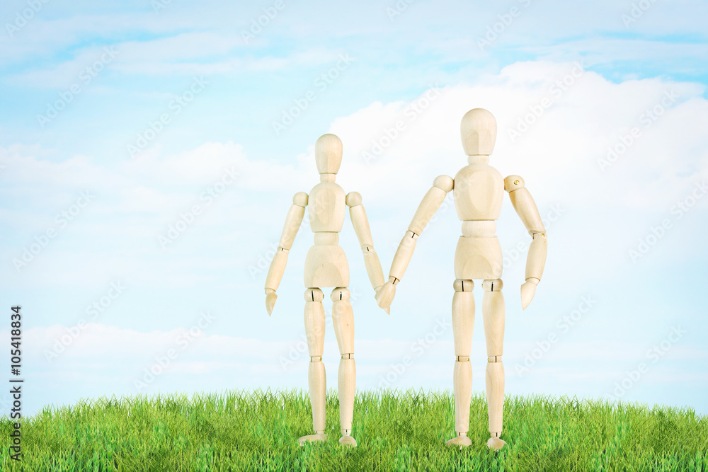 Happy couple stands on the green lawn outdoor. Abstract image with a wooden puppets Happy couple stands on the green lawn outdoor. Abstract image with a wooden puppets