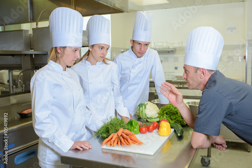 Chef giving instructions to trainee cooks