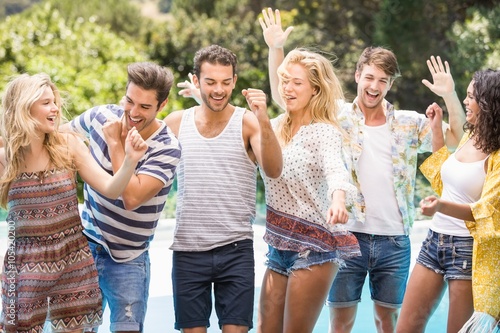 Group of happy friends dancing near pool