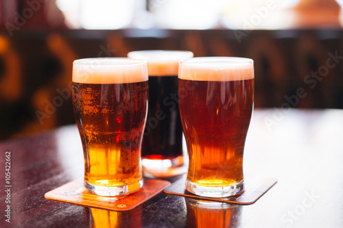 Glasses of light and dark beer on a pub background.