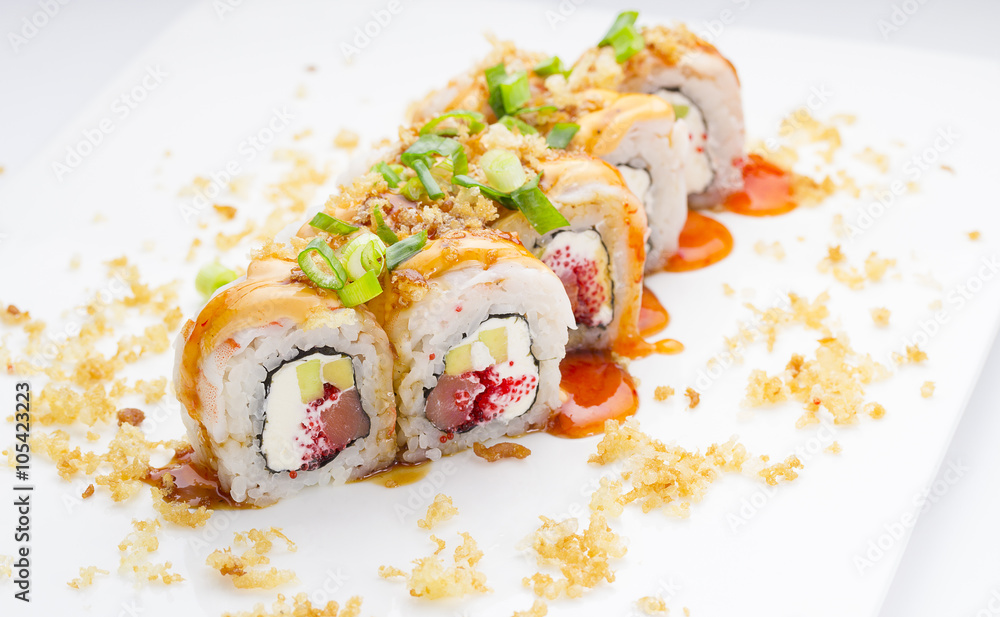 Sushi with shrimp avocado salmon and cheese strewed with green onion. Crunch Roll. With delicious sauces. On a plate over white background. Sushi with shrimp avocado salmon and cheese strewed with green onion. Crunch Roll. With delicious sauces. On a plate over white background.