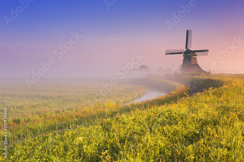 Traditional Dutch windmill at sunrise on a foggy morning