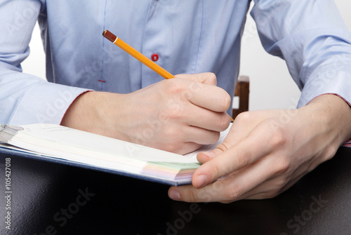 мужчина пишет в блокноте карандашом 
