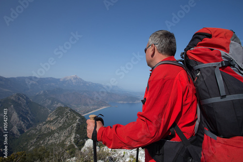 A traveler stands on top of a mountain and looks out to sea.