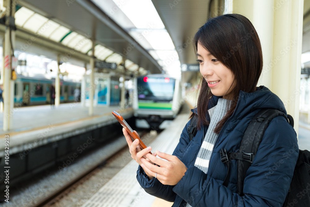 Woman use of cellphone and standing on train platform