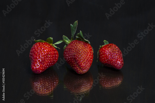 Wallpaper Mural Three  fresh strawberries placed on a mirror black wooden table Torontodigital.ca