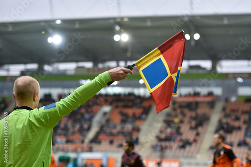  Linear referee with the raised flag during football match