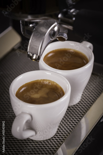 two cups of espresso poured from a espresso machine 