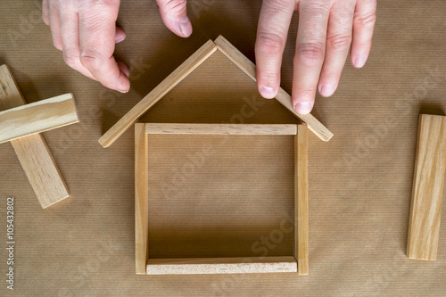 Mains construisant une maison en blocs de bois