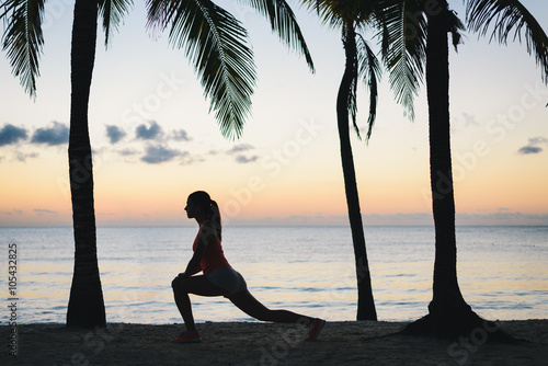 Fitness woman stretching for warming up before running at tropical caribbean beach in Riviera Maya, Mexico. Female athlete exercising during vacation at dawn. photo