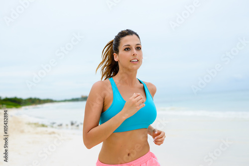 Fitness woman running at the beach on summer vacation. Healthy female athlete training outdoor.