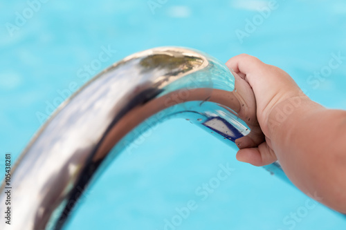 Child s hand holding a handrail in a swimming pool