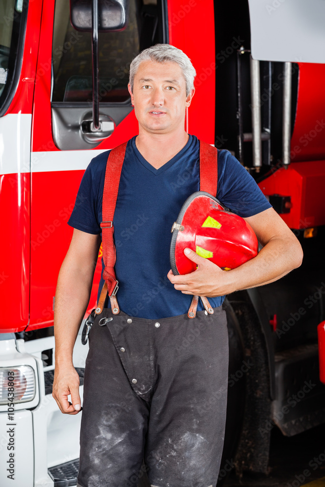 Naklejka premium Confident Firefighter Holding Red Helmet