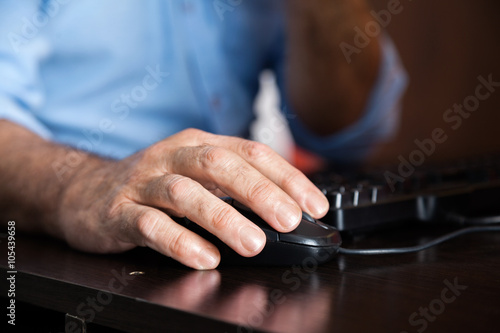 Man Using Computer Mouse At Desk In Class