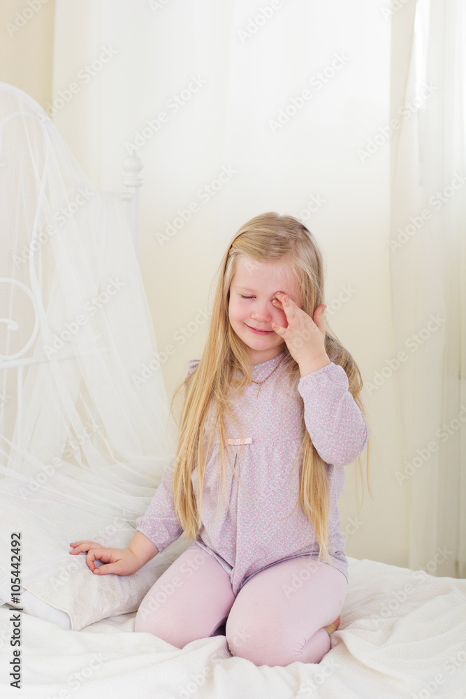 Tired cute child girl rubing eyes in the bed Tired cute child girl rubing eyes in the bed