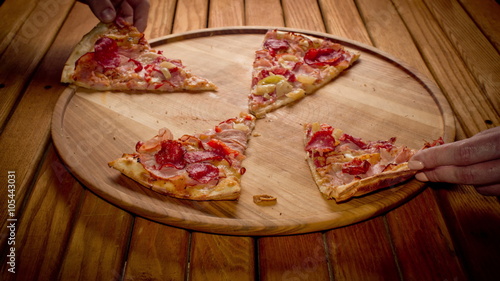 Top view hands taking big pizza cuts from wooden  plate on the table - stop motion animation, 4K
