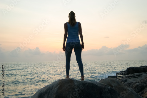 the beautiful girl sitting on stones and looking in a distance  the girl at sunset to meditate in silence  beautiful body .concept .Siluet lonely girl sitting on the precipice of a cliff at sunset. 