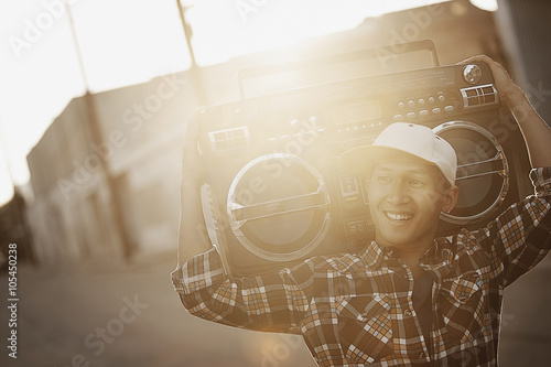 A young man with a boombox on his shoulder on the street of a city, 
