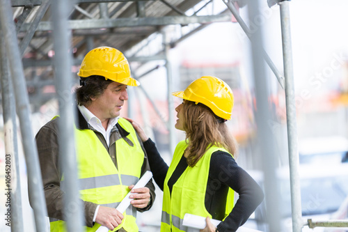 Male and female engineers talking at a construction site