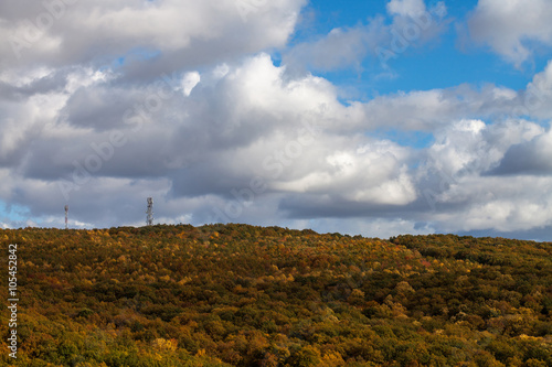 autumn landscape with colorful forest, blue sky and clouds