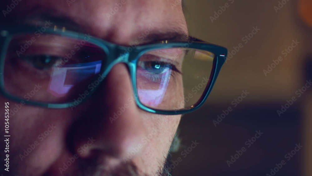 Portrait of a young man with glasses who works at night. Close up shot, display reflections Portrait of a young man with glasses who works at night. Close up shot, display reflections