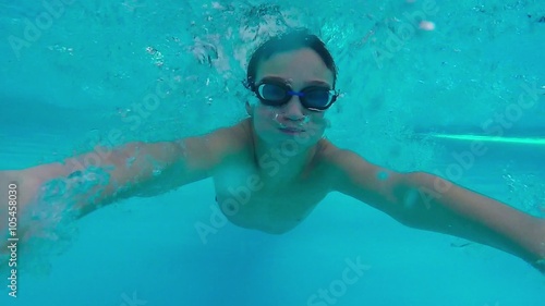 Teen boy swimming underwater in pool.