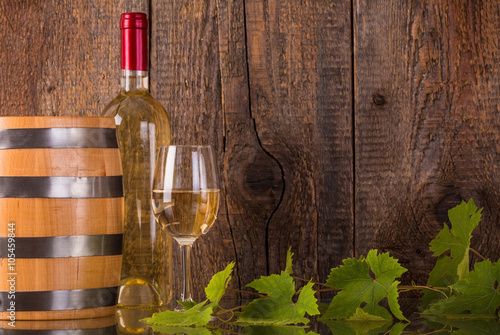 Glass of wine with white bottle and barrel photo