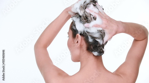 Beautiful young woman with attractive smile soaping and massaging her head