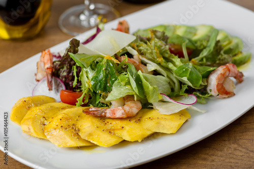 restaurant dish with shrimp and mango in a white plate