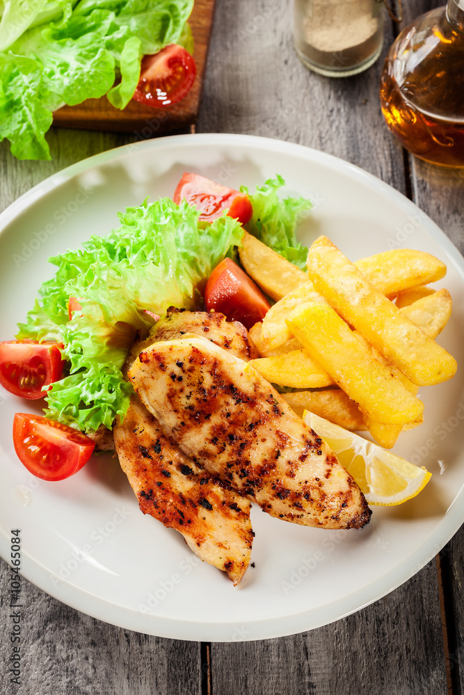 Grilled chicken breasts served with fries and fresh salad