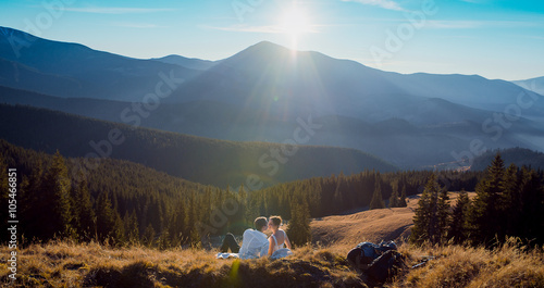 Tablou pe pânză Romantic wedding couple kissing while lying on the grass in mountains