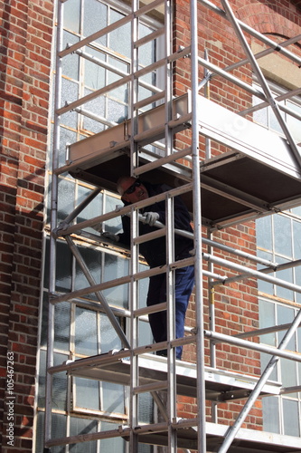A painter and decorator working from a scaffold tower © markim