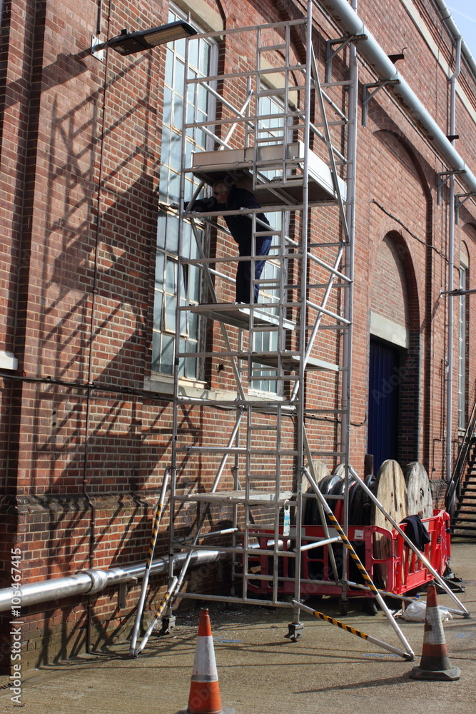 A painter and decorator working from a scaffold tower A painter and decorator working from a scaffold tower