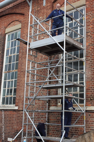 Two painter and decorators working from a scaffold tower